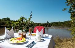 A dining table in front of a lake at Mara Serena Safari Lodge